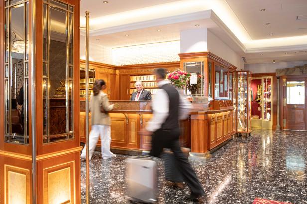 Ein Hotelangestellter eilt mit einem Koffer durch die Lobby des Hotel Stefanie.
