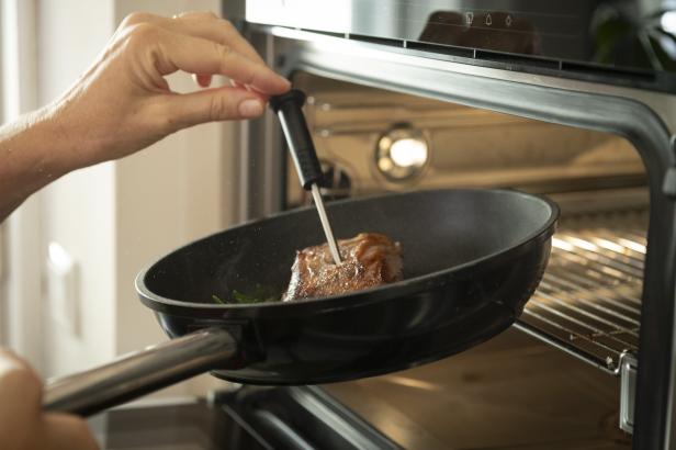 Eine Person brät ein Steak in einem Ofen.