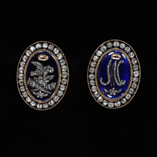 Zwei ovale Broschen mit Diamanten und blauen Emaille-Intarsien, eine mit Adler, die andere mit einem Monogramm.