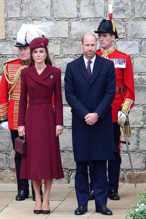 Prinz William und Prinzessin Kate bei einem formellen Anlass mit zwei Gardesoldaten.