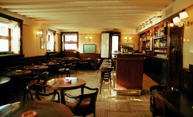 Innenansicht einer Bar mit Tischen, Stühlen und einer Theke.