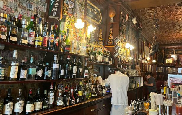 Eine Bar mit einer großen Auswahl an Spirituosen und dekorativen Elementen wie Wimpeln und Geldscheinen.