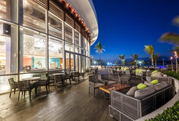 Ein Außenbereich eines Resorts mit Tischen, Stühlen und Sofas bei Nacht.