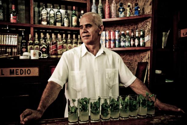 Ein Barkeeper steht hinter einer Bar mit vorbereiteten Mojitos.