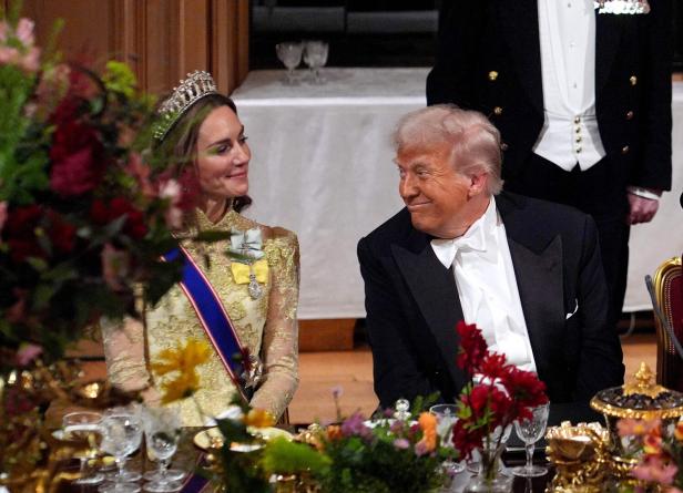 Prinzessin Kate mit Tiara und Donald Trump sitzen beim Staatsbankett nebeneinander. Sie lächelt mit geschlossenem Mund, blickt auf ihn herab. Er lächelt ebenfalls.