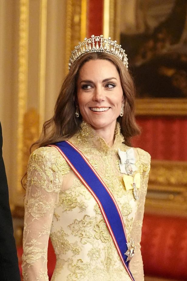 Prinzessin Kate mit Tiara Kate trägt ein goldenes Kleid mit Spitze, eine Tiara und eine blaue Schärpe.