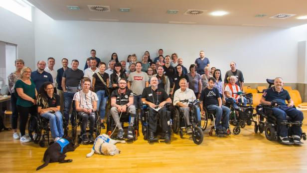 Gruppe von Menschen, einige davon in Rollstühlen, posieren für ein Foto.