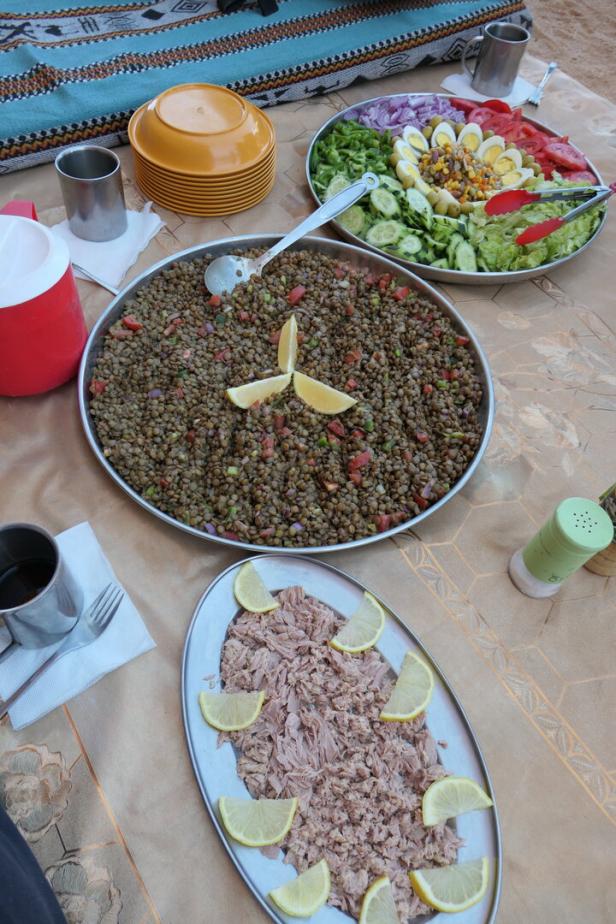 Ein Tisch mit Linsen, Thunfisch mit Zitrone und einem gemischten Salat.