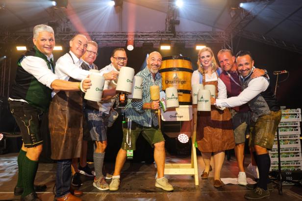 Menschen mit Bierkrügen beim Bierfass