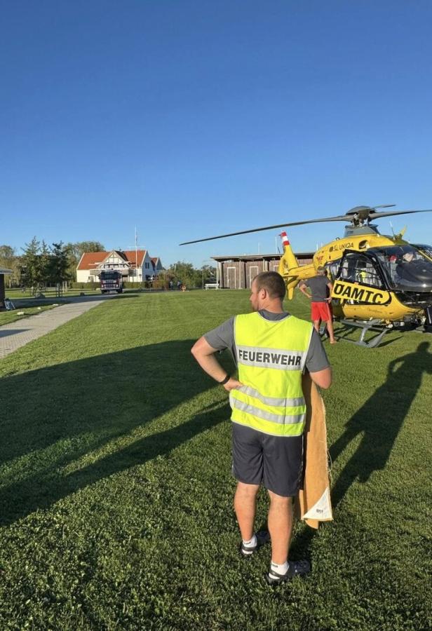 Feuerwehrmann, im Hintergrund ein Notarzthubschrauber