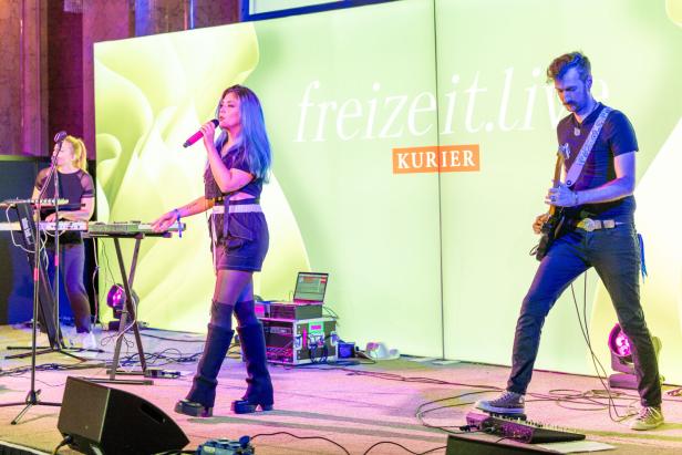 Eine Sängerin mit blauen Haaren tritt mit ihrer Band auf einer Bühne auf.