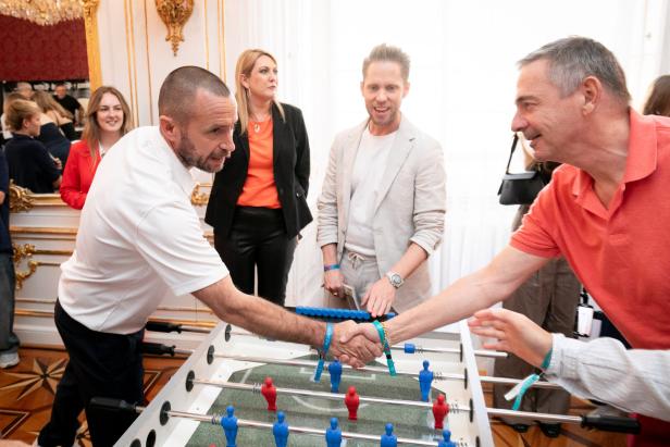 Zwei Männer schütteln sich die Hände über einem Tischfußballspiel.