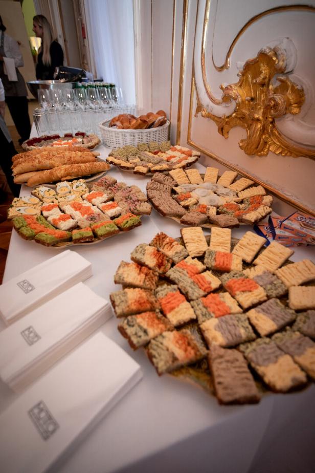 Ein Tisch ist mit verschiedenen Platten mit belegten Broten und Brötchen gedeckt.