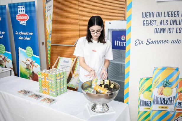 Eine junge Frau steht an einem Stand mit Radlberger-Getränken in Eis gekühlt.