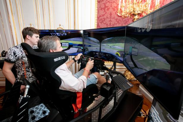 Ein Mann spielt mit einem Rennsimulator, während ein anderer Mann zusieht.