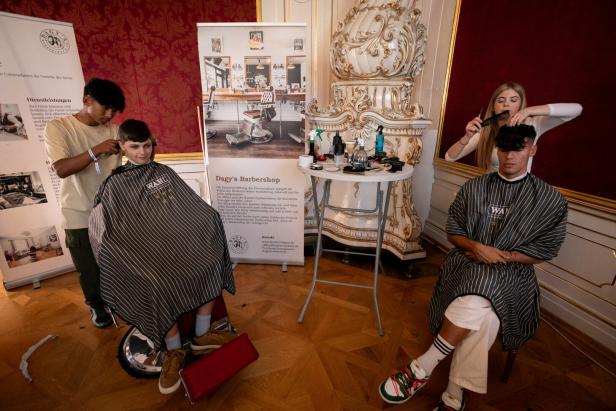 In einem Barbershop werden zwei Kunden von Friseuren bedient.