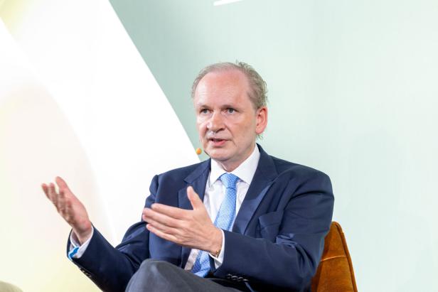 Ein Mann in einem Anzug gestikuliert während einer Präsentation.