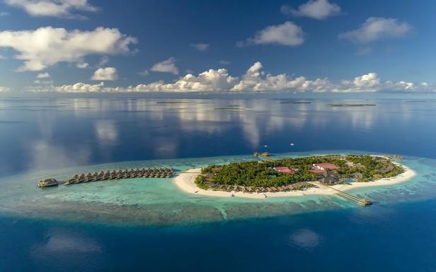 Insel von oben in einem Atoll, sie ist eher klein, es gibt ein paar Stege ins Meer.