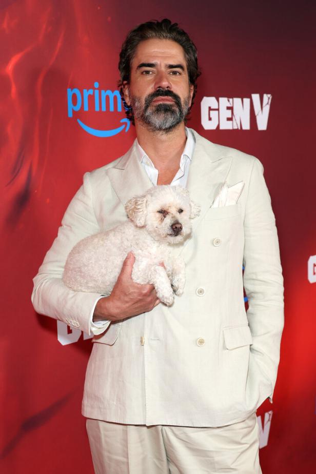 Schauspieler Hamish Linklater hält einen kleinen, weißen Hund.