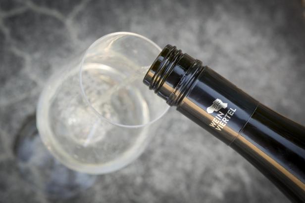Weißwein aus einer Flasche „Weinviertel DAC“ wird in ein Glas gegossen.