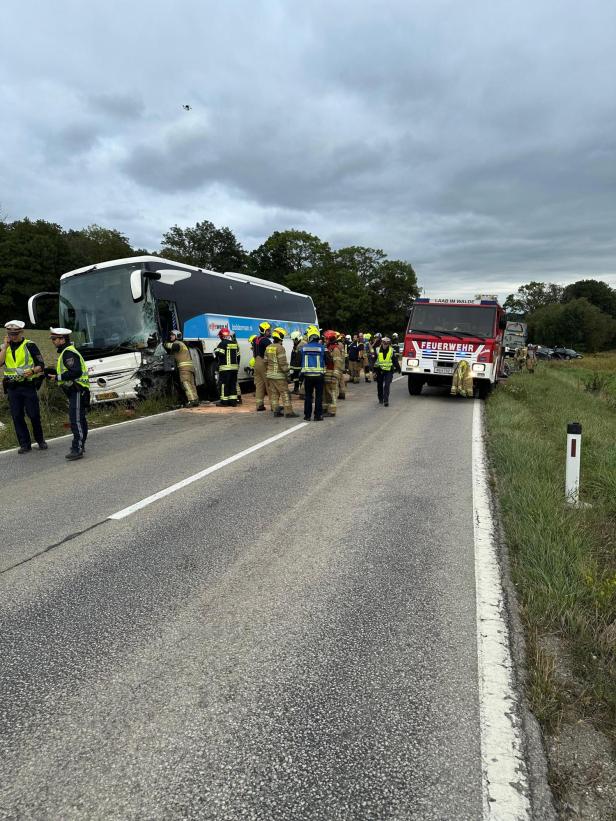 Menschen stehen um verunfallten Bus.