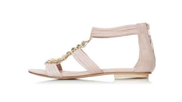 Eine rosafarbene Sandale mit goldenen Ketten und Perlenverzierungen.