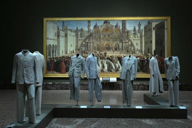 Eine Ausstellung mit Giorgio Armani-Anzügen vor einem Gemälde in einem Museum.