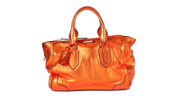 Eine orangefarbene Handtasche aus Leder auf einem weißen Hintergrund.