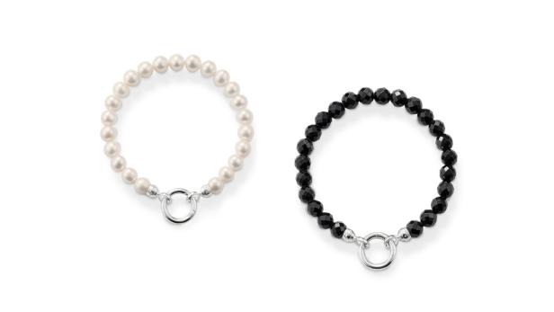 Zwei Armbänder, eines aus Perlen und eines aus schwarzen Onyx-Steinen, liegen auf einem weißen Hintergrund.