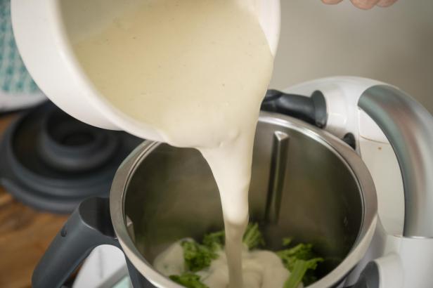 Eine Person gießt Flüssigkeit in einen Mixer.