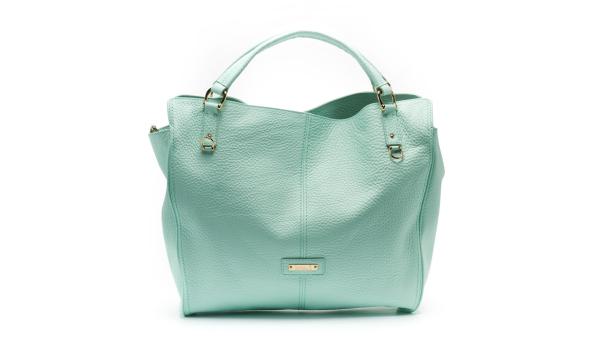 Eine hellblaue Handtasche aus Leder mit goldenen Akzenten vor einem weißen Hintergrund.