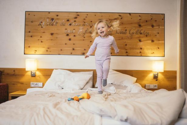 Ein Kind springt auf einem Bett rum. 