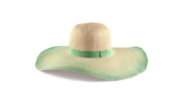 Ein Strohhut mit breiter Krempe und einem grünen Band liegt auf einem weißen Hintergrund.