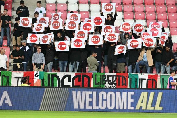 Italienische Fans halten auf der Tribüne Stoppschilder als Protest gegen Israels Gaza-Krieg
