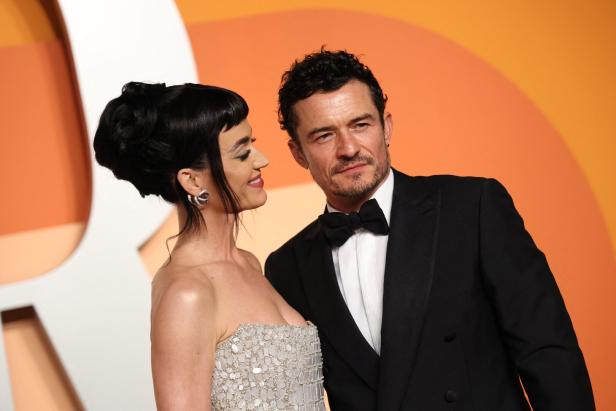 Katy Perry und Orlando Bloom posieren auf einem Event, sie im glitzernden Kleid, er im Smoking.
