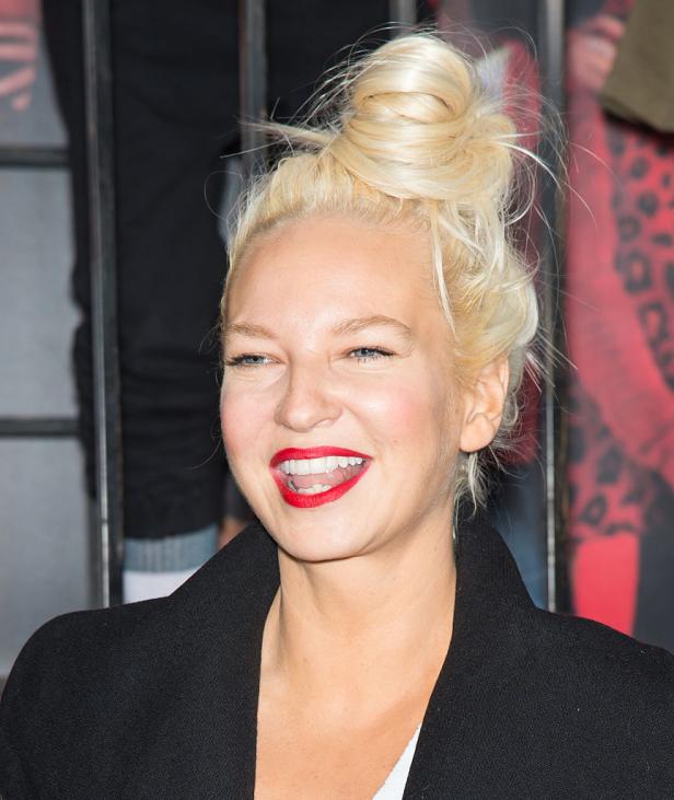 Sängerin Sia mit blondem Dutt und rotem Lippenstift.