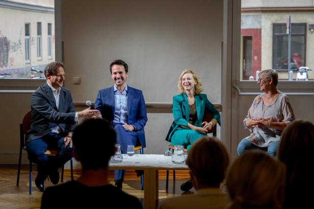 Zu sehen sind Holzleitner und Wiederkehr bei einer Diskussion mit Schülerinnen und Schülern.