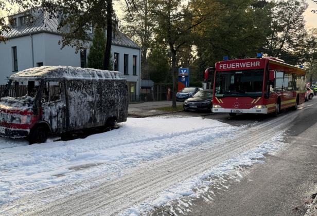 A burnt-out van is covered in foam after being extinguished by fire fighters