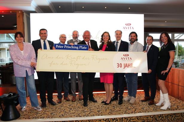 Zehn Personen stehen zusammen und halten ein großes Schild mit der Aufschrift „AVITA 30 Jahr“ und einem weiteren blauen Schild.