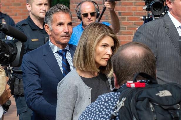 Lori Loughlin und ihr Ehemann Mossimo Giannulli umgeben von Kameras und Reportern.