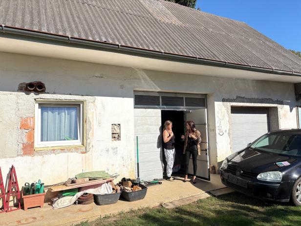 Zwei Frauen stehen vor einer Garage neben einem schwarzen Auto.