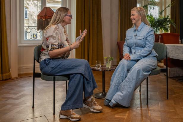 Lisa Trompisch und Beatrice Egli sitzen sich gegenüber und unterhalten sich in einem Raum mit Parkettboden.