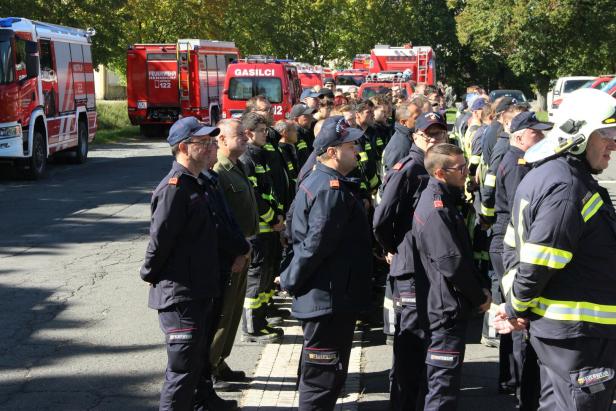 Eine Gruppe Feuerwehrleute steht vor mehreren roten Feuerwehrfahrzeugen.