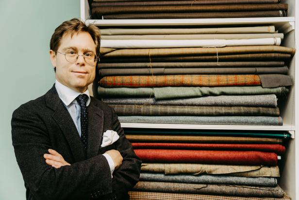 Maß-Salon Possanner: Der Schneider steht vor einem Regal voll mit zusammengelegtem Stoff.