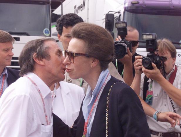 Prinzessin Anne bekommt einen Kuss von Jackie Stewart, während Fotografen die Szene festhalten.