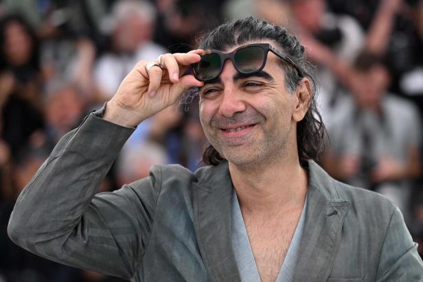 Ein Mann schiebt seine Sonnenbrille nach oben und lacht.