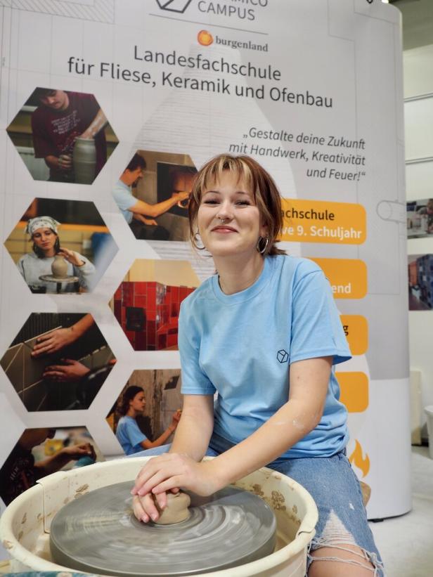 Eine junge Frau sitzt an einer Töpferscheibe vor dem Stand der Landesfachschule Burgenland.