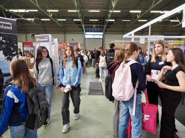 Viele junge Leute besuchen eine Bildungsmesse in einer großen Halle.