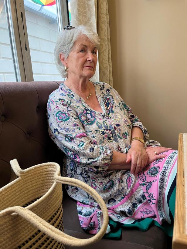Die 82-jährige Elisabeth Pfriemer sitz in einem bunt gemusterten Kleid in Blau-Rosa-Tönen in einem Kremser-Cafe