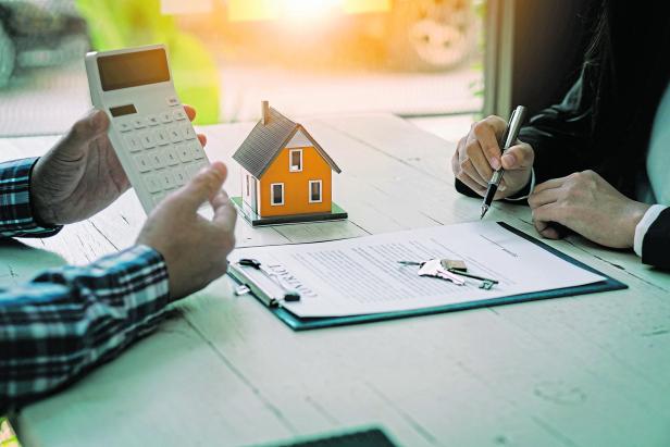 Real estate professionals offer their clients contracts to discuss home purchases, insurance or real estate loans. Home sales agents sit at the office with new home buyers in the office.